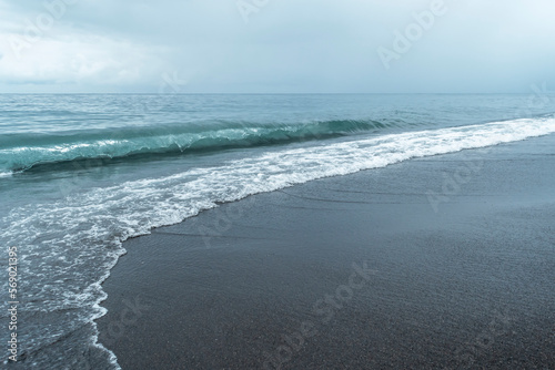 Canvas Print Black volcanic sand on the beach with waves.