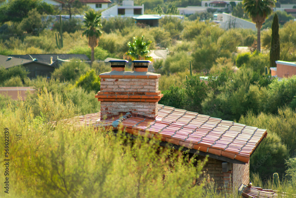 Chimney on top of adobe house with flat red roof tiles in the hills of arizona wilderness in the sonora desert landscapes