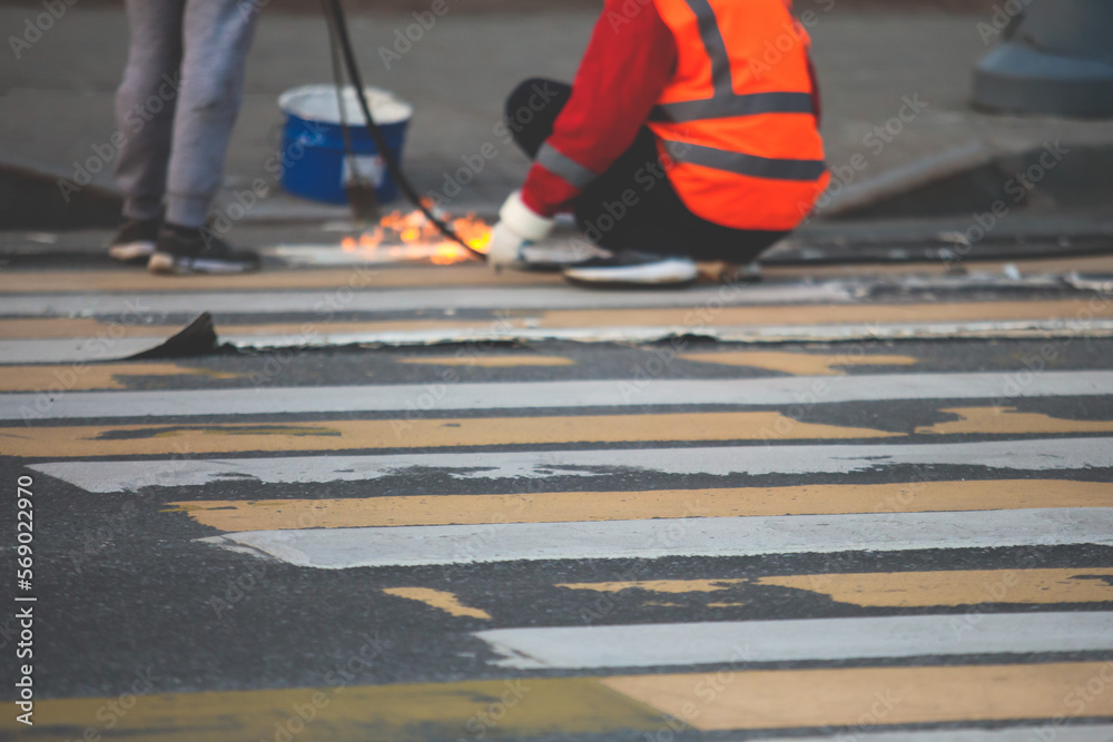 Process of making new road surface markings with a line striping machine, workers improve city infrastructure, demarcation marking of pedestrian crossing with hot melted paint on asphalt pavement Process of making new road surface markings with a line striping machine, workers improve city infrastructure, demarcation marking of pedestrian crossing with hot melted paint on asphalt pavement