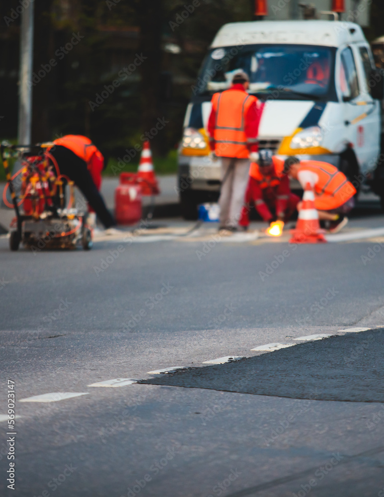 Process of making new road surface markings with a line striping machine, workers improve city infrastructure, demarcation marking of pedestrian crossing with hot melted paint on asphalt pavement Process of making new road surface markings with a line striping machine, workers improve city infrastructure, demarcation marking of pedestrian crossing with hot melted paint on asphalt pavement