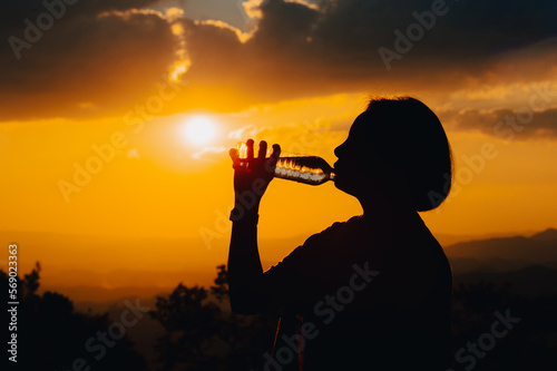 silhouette of a woman drinking water drinking water in the sunset
