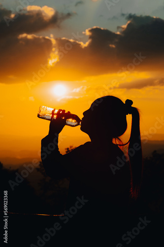 silhouette of a woman drinking water drinking water in the sunset