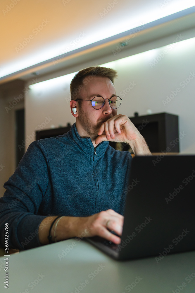 A young man is using his laptop at night for business or studying A young man is using his laptop at night for business or studying