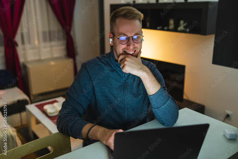 A young man is using his laptop at night for business or studying A young man is using his laptop at night for business or studying