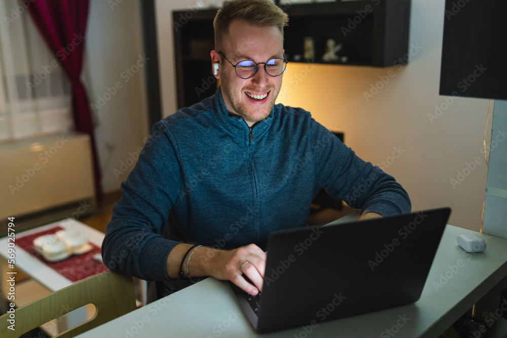 A young man is using his laptop at night for business or studying A young man is using his laptop at night for business or studying