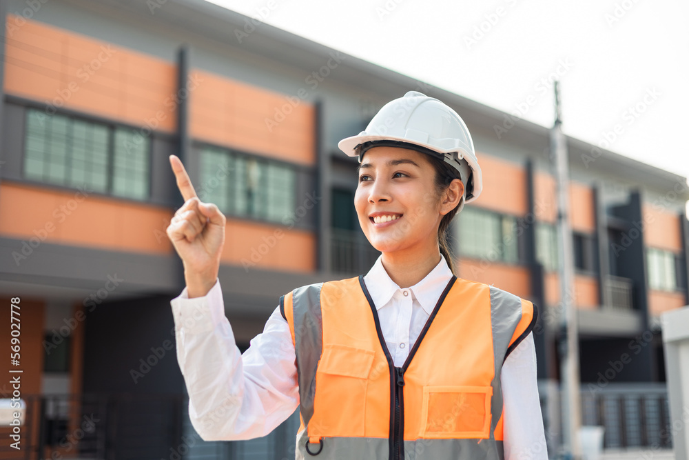 Confident engineer woman standing at modern home building construction. Architect with white safety helmet at construction site. Mechanic service factory Professional work job occupation in uniform. Confident engineer woman standing at modern home building construction. Architect with white safety helmet at construction site. Mechanic service factory Professional work job occupation in uniform.