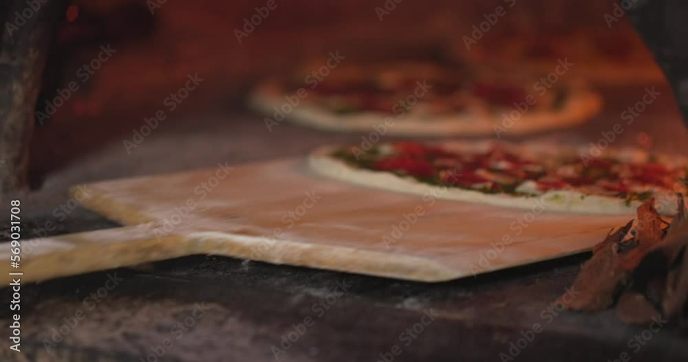 Baking the smoking hot delicious pizza in a traditional Italian oven with wood fire flame. Spin and turn, pull in and pull off in slow motion. 