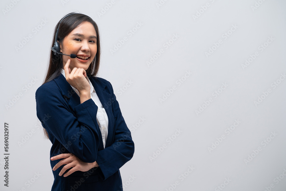 Beautiful Asian call center operator talking with customer using headset and microphone isolated on grey background. Beautiful Asian call center operator talking with customer using headset and microphone isolated on grey background.