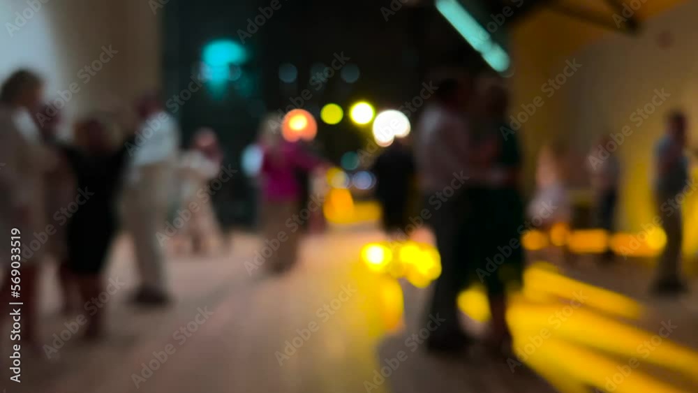 Blurred image of people dancing at a special event. Colorful lights reflect and illuminate the lens Blurred image of people dancing at a special event. Colorful lights reflect and illuminate the lens