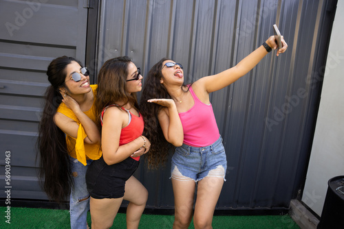 Portrait of beautiful indian women having fun party taking pictures with smart phone,Group of young girl friends in sunglasses and casual clothes laughing and celebrating all together. summer vacation © gajendra