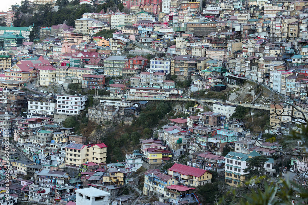 Many houses on a densely populated hillside in Shimla Northern India. House in the foothills of the Himalaya mountains capital of Himachal Pradesh. Ariel view of Shimla town.