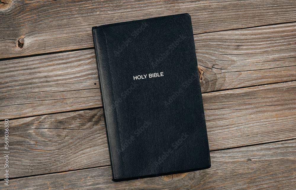 Black Bible on a wooden background close up, top view, concept of christian life, Bible study. Black Bible on a wooden background close up, top view, concept of christian life, Bible study.