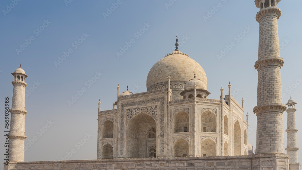 Beautiful ancient white marble Taj Mahal against the blue sky. The symmetrical mausoleum with arches, domes, minarets is decorated with ornaments, inlays of precious stones. India. Agra.
