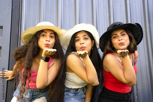 Portrait of beautiful fashionable indian women having fun party,Group of young brunette girl friends hats and casual trendy clothes posing flying kissing all together. summer vacation and holidays