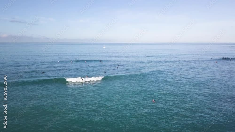 Surfers far away in the background riding waves on waikiki beach in honolulu hawaii on turquoise water, AERIAL DOLLR TILT Surfers far away in the background riding waves on waikiki beach in honolulu hawaii on turquoise water, AERIAL DOLLR TILT