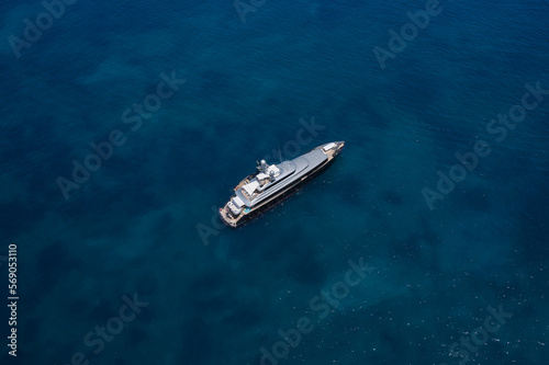 Light gray large super yacht in the morning sun top view at high altitude. Large innovative modern yacht deck made of teak wood in the open sea at anchor aerial view. © Berg