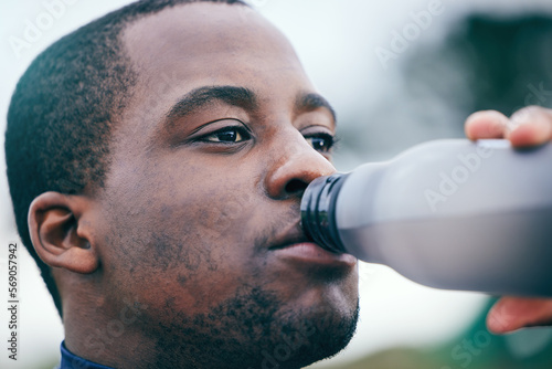 Fitness, break and face of black man drinking water to hydrate after running, exercise and workout. Health, sports and African athlete with a bottle drink after training, sports and cardio in Germany