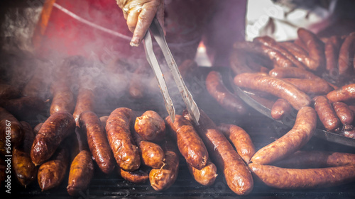 A close-up view of hands of a man grilling homemade sausages photo