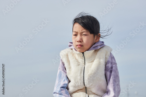 冬の外で寒さを感じる寂しい小学生の女の子の様子
