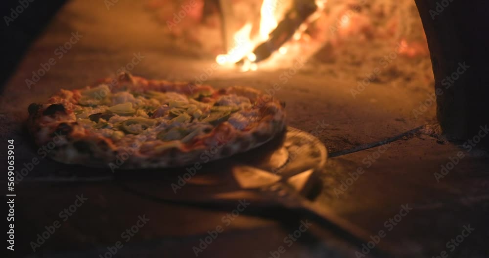 Baking the smoking hot delicious pizza in a traditional Italian oven with wood fire flame. Spin and turn, pull in and pull off in slow motion. 