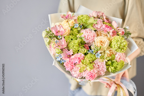 Florist woman creates beautiful bouquet of mixed flowers with varietal carnations, bush veronica, oxypetalum, ranunculus. European floral shop concept. Handsome fresh bunch. Education, master class