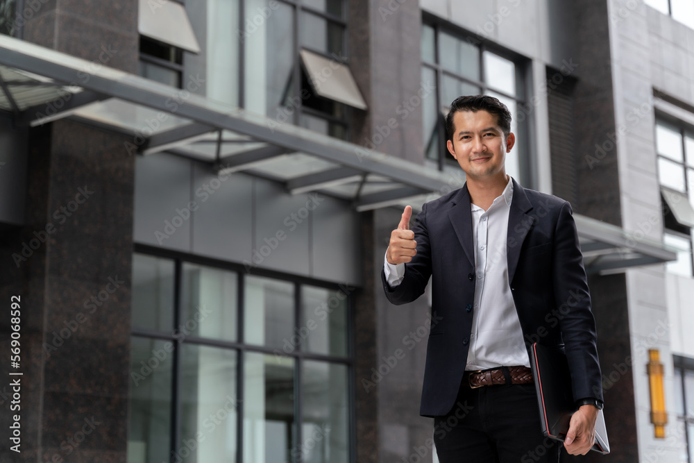 Asian business man looking at the camera and giving a thumbs up in urban public space. Asian business man looking at the camera and giving a thumbs up in urban public space.