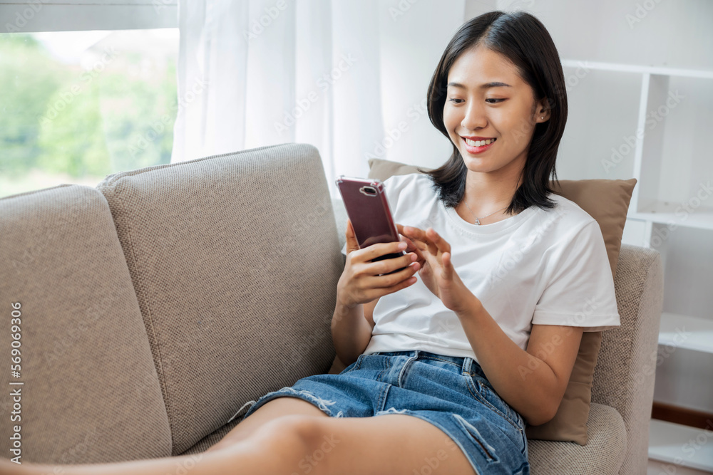 Young asian girl sitting on sofa using mobile phone in the living room. Young asian girl sitting on sofa using mobile phone in the living room.