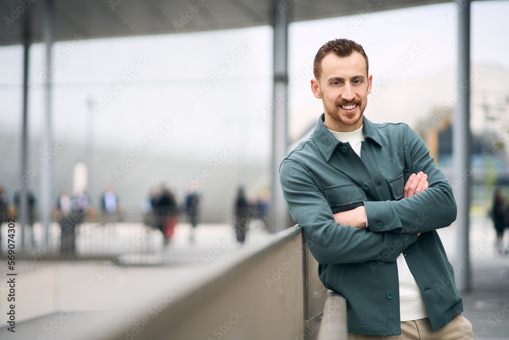 Portrait of smiling  handsome modern man with arms crossed looking at camera on the street, copy space. People concept