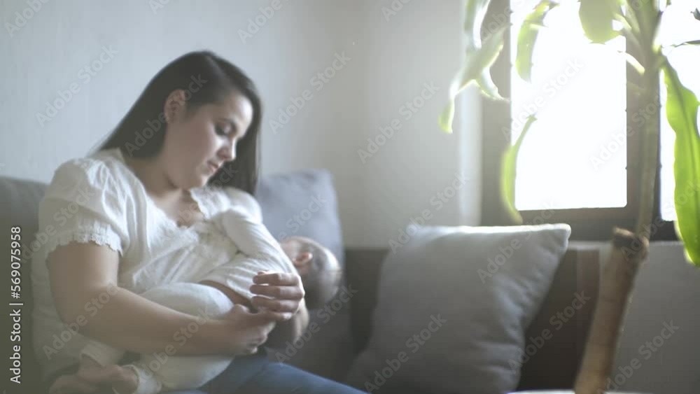madre hispana sentada arrullando a bebé latino mientras realiza lactancia materna, LME
