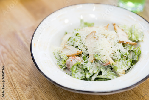 Close up of Caesar salad in a big white plate  in a cafe