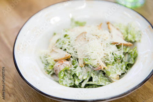 Close up of Caesar salad in a big white plate in a cafe