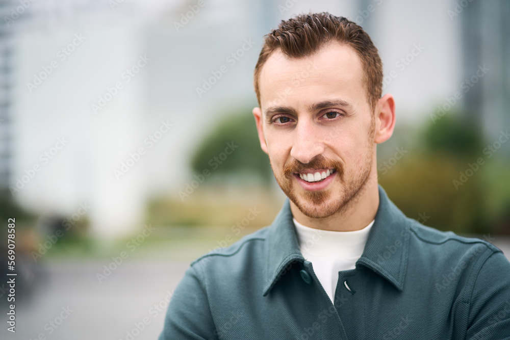 Happy handsome modern man smiling toothy and looking to camera while posing at street. Positive lifestyle concept Happy handsome modern man smiling toothy and looking to camera while posing at street. Positive lifestyle concept