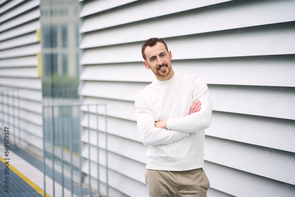 Portrait of smiling confident man looking at camera arms crossed on the wall background Portrait of smiling confident man looking at camera arms crossed on the wall background