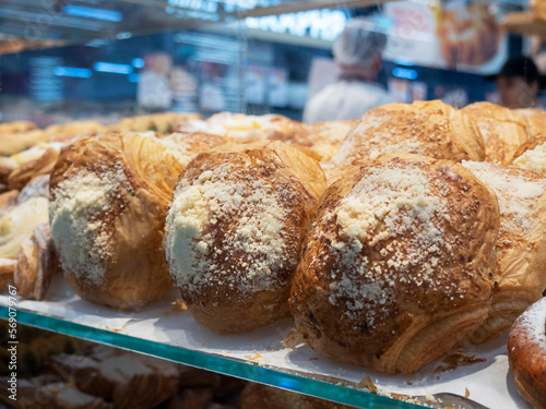 Image of baked goods behind glass on a shelf .