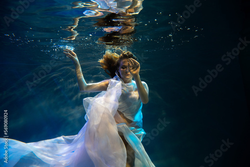 Young beautifull caucasian woman in dress under water