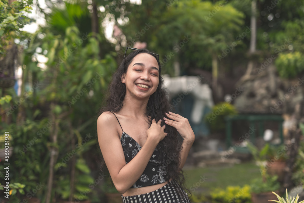 A pretty young Filipina woman with curly hair wearing a nice black top and long skirt feeling fresh at the garden. A pretty young Filipina woman with curly hair wearing a nice black top and long skirt feeling fresh at the garden.