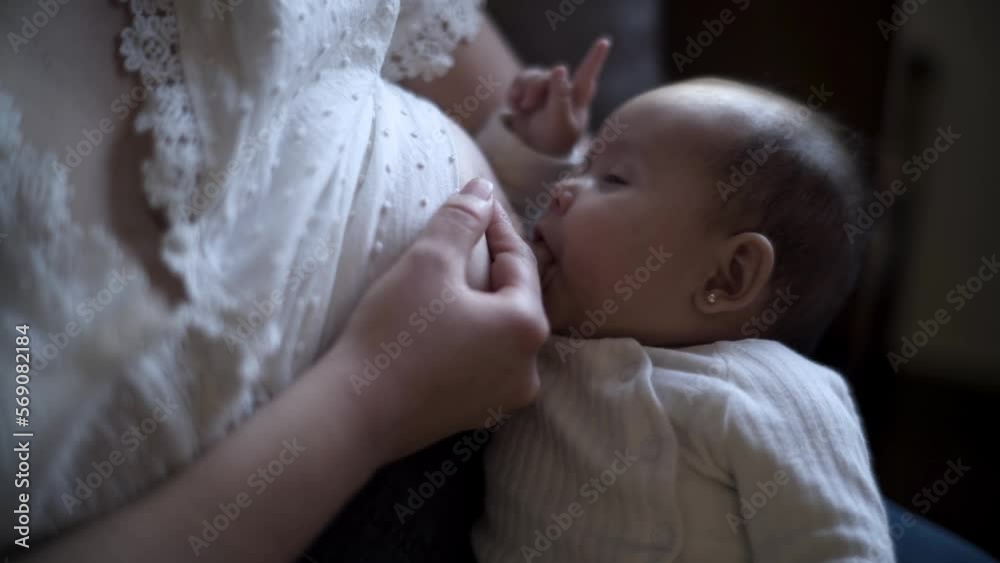 bebé succionando de pecho de madre sentada en sofá de casa mientras hijo intentando dormir