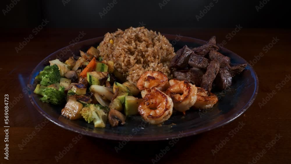 Dinner of hibachi shrimp and steak with fried rice mixed vegetables, slider 4K Dinner of hibachi shrimp and steak with fried rice mixed vegetables, slider 4K