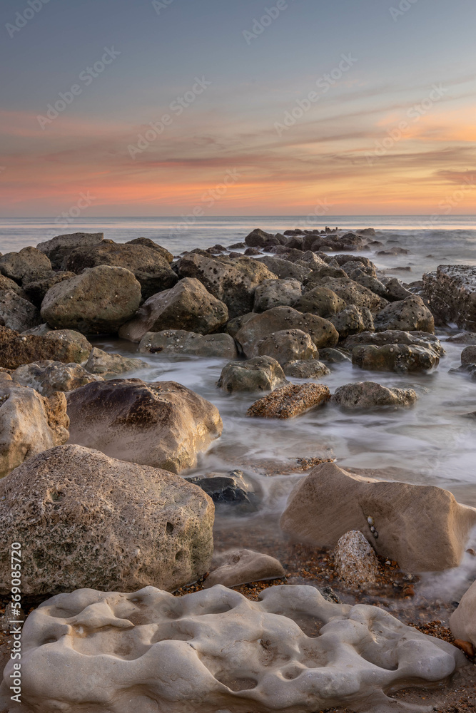 Ocean scene with low sun on the horizon, some rocks in foreground and mid ground with blurred waves around them plus a few colourful clouds. Ocean scene with low sun on the horizon, some rocks in foreground and mid ground with blurred waves around them plus a few colourful clouds.