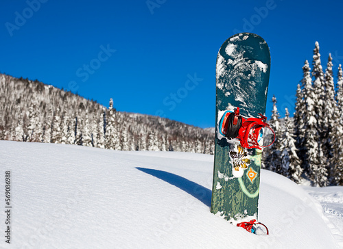 snowboard stands in the snow on a sunny day outdoors