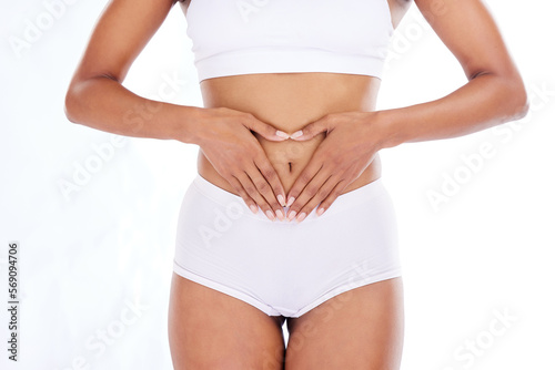 Hands, heart and stomach with a woman in studio isolated on a white background for gut health or weightloss. Fitness, wellness and colon with a female posing in her underwear on blank space