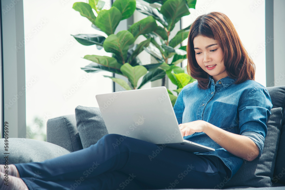 Happiness Asian Woman working from home using laptop online meeting in home office. Happy relax time asian business woman typing keyboard use notebook laptop Smiling, laughing at home office. Happiness Asian Woman working from home using laptop online meeting in home office. Happy relax time asian business woman typing keyboard use notebook laptop Smiling, laughing at home office.