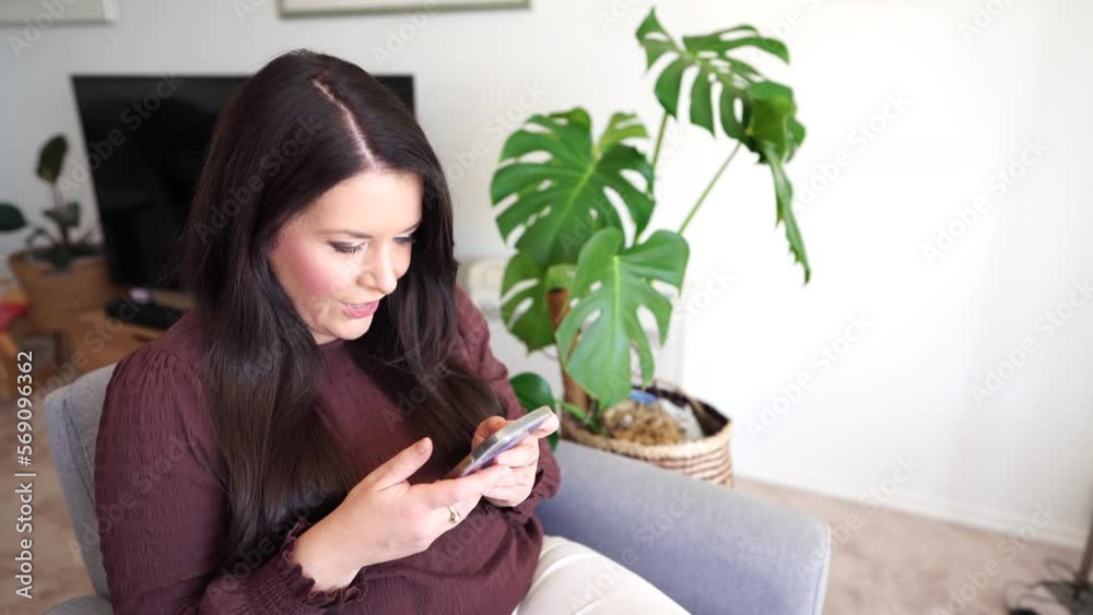Girl on her smart phone texting friends, messaging people. Woman laughing talking to family. Model using technology in her living room in a white house Girl on her smart phone texting friends, messaging people. Woman laughing talking to family. Model using technology in her living room in a white house