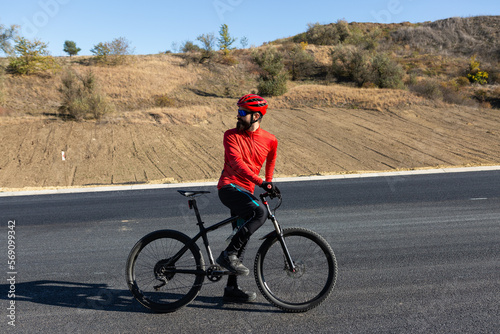 Cyclist riding bicycle on road against clear sky. A man in an outfit stands with a bicycle on an autumn sunny day.
