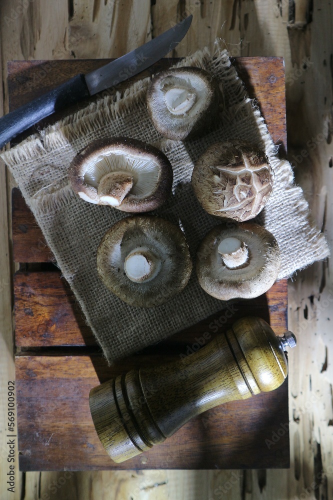 shitake mushroom, knife and wooden spice grinder on wooden tray