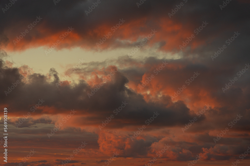 Sunset sky. Frightening dark clouds are illuminated by the red-orange light of the sun. Beautiful sky. Natural background.