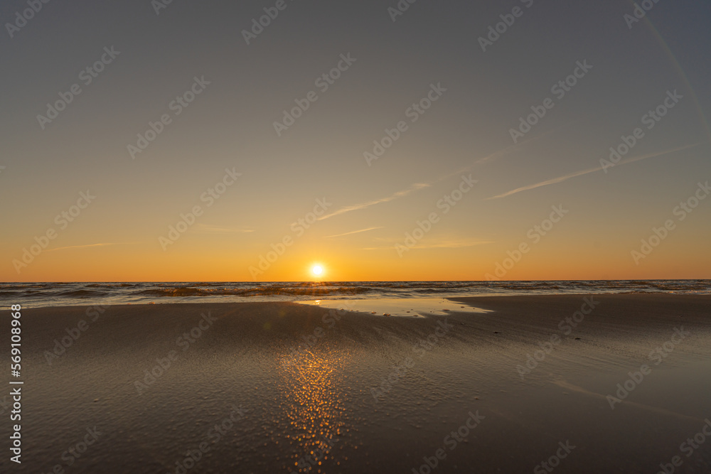 Sunset in a cloudless sky on the coast of the Gulf of Finland in Ust-Narva. The sky is clear, the waves gently roll on the sand. Estonia, Narva-Jyesuu. Natural background. Space for text. Sunset in a cloudless sky on the coast of the Gulf of Finland in Ust-Narva. The sky is clear, the waves gently roll on the sand. Estonia, Narva-Jyesuu. Natural background. Space for text.
