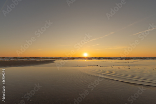 Sunset in a cloudless sky on the coast of the Gulf of Finland in Ust-Narva. The sky is clear  the waves gently roll on the sand. Estonia  Narva-Jyesuu. Natural background. Space for text.