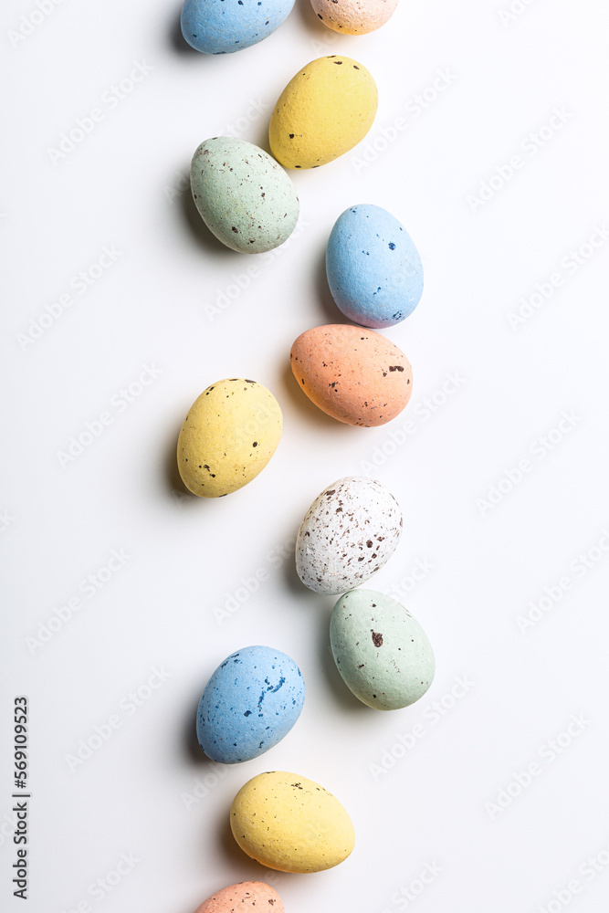 Easter composition of colorful quail eggs over white background. Springtime holidays concept with copy space. Top view