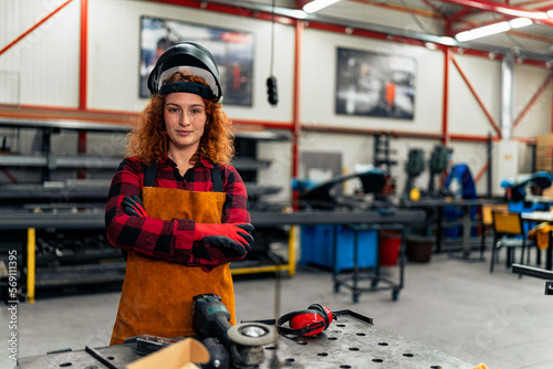 A young woman poses in front of her workshop, the first generation business owner in her family photo